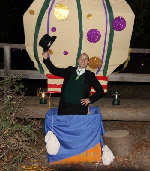A Hidden Villa intern dressed as the Wizard of Oz stands in a fake hot-air balloon. He allowed parents to take a picture of their children with him to remember Halloween on the Farm. Photo by Dylan Tsai.