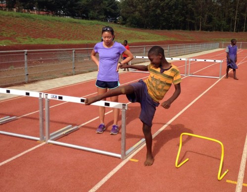 Junior Madeleine Yip assists a child across a hurdle. 