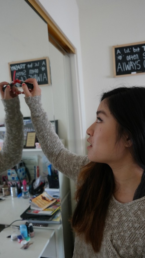 Junior Emily Leung writes a message on her bedroom mirror. Leung writes reminders on her mirror regularly using lipstick. Photo by Rhonda Mak 